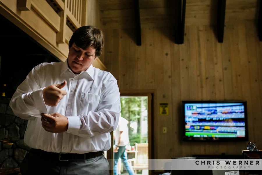 Lake Tahoe groom buttoning his shirt and watching the game before a Lake Tahoe Tree Company wedding.