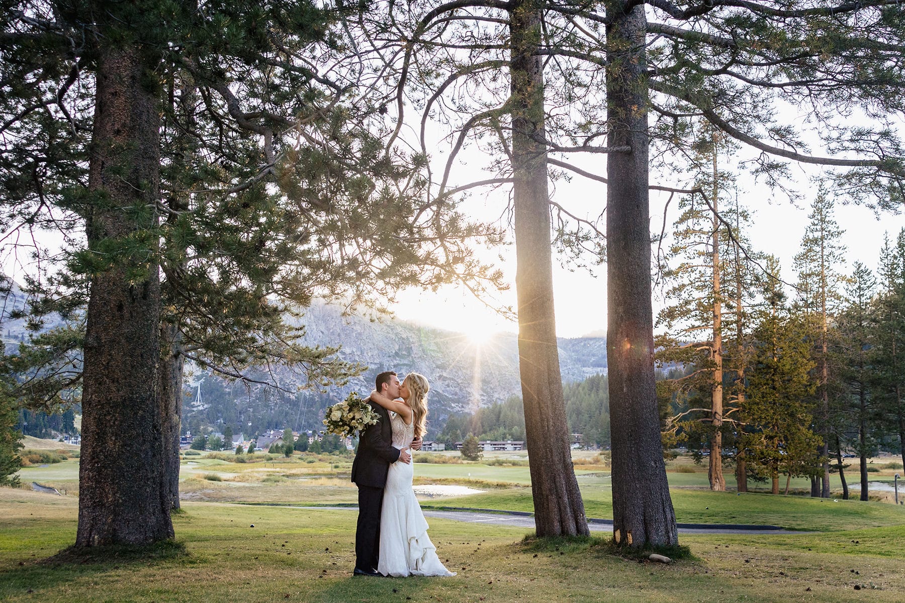 As the sun's last rays illuminate Olympic Valley, a bride and groom exchange a kiss at the edge of the Resort at Squaw Creek. 