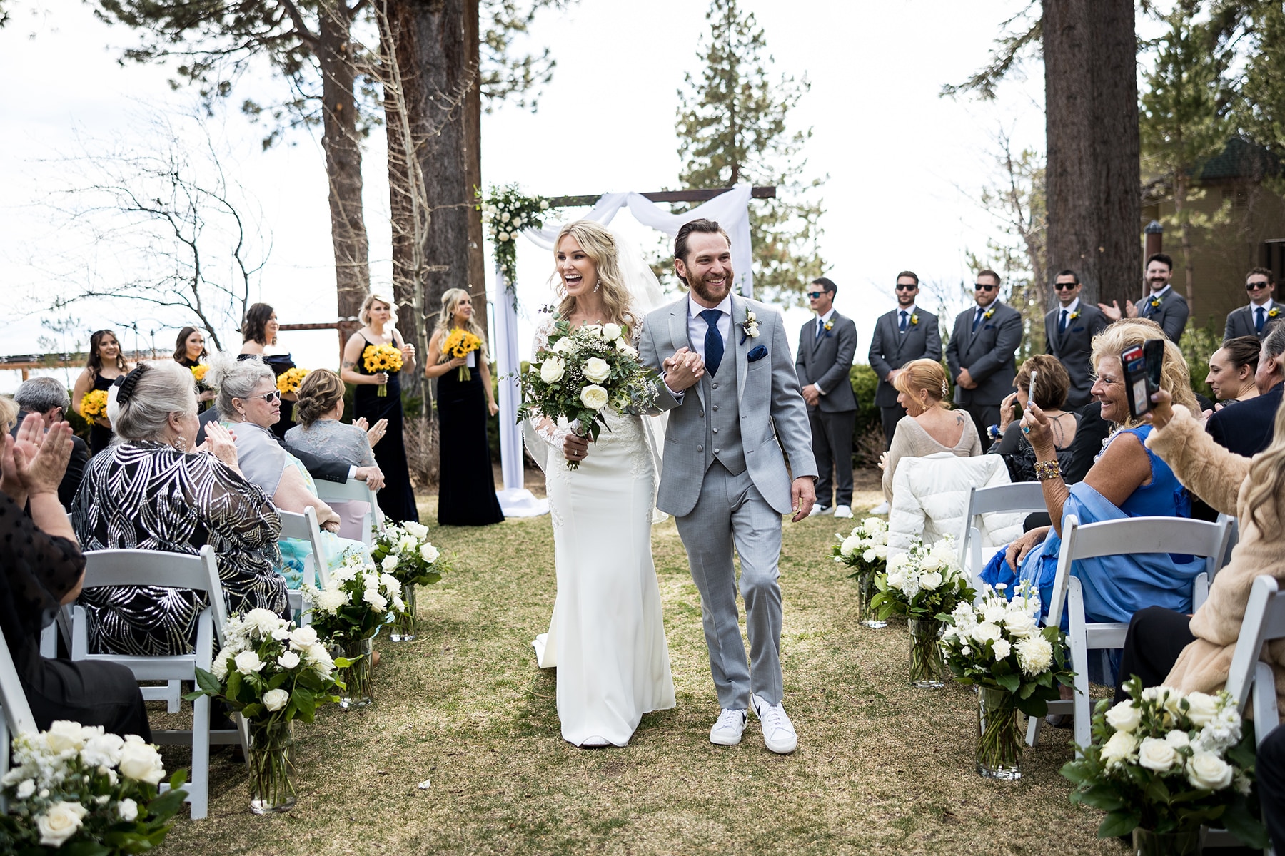 A bride and groom smile at their guests as they recede from their Tahoe Hyatt wedding ceremony on the Cottage Green.