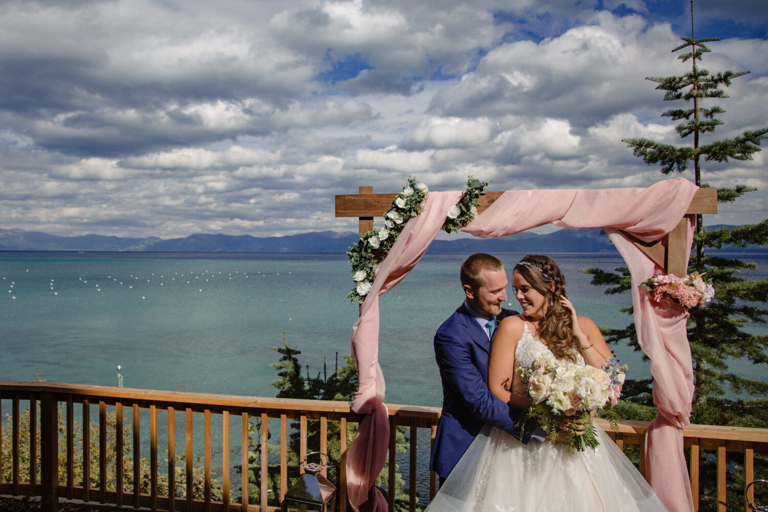 Lakeside portrait of the couple under their DIY wooden wedding arch.