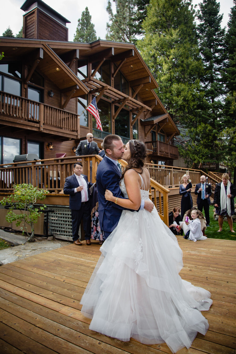 A bride and groom perform their first dance on a wooden deck.