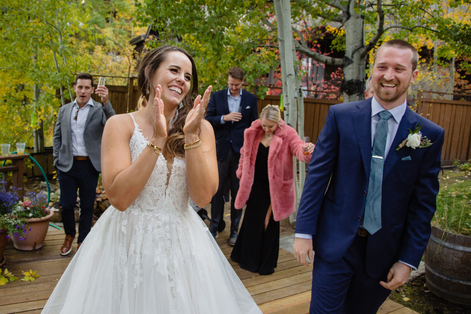 Happy newlyweds celebrate at their outdoor fall wedding with yellow leaves in the background.
