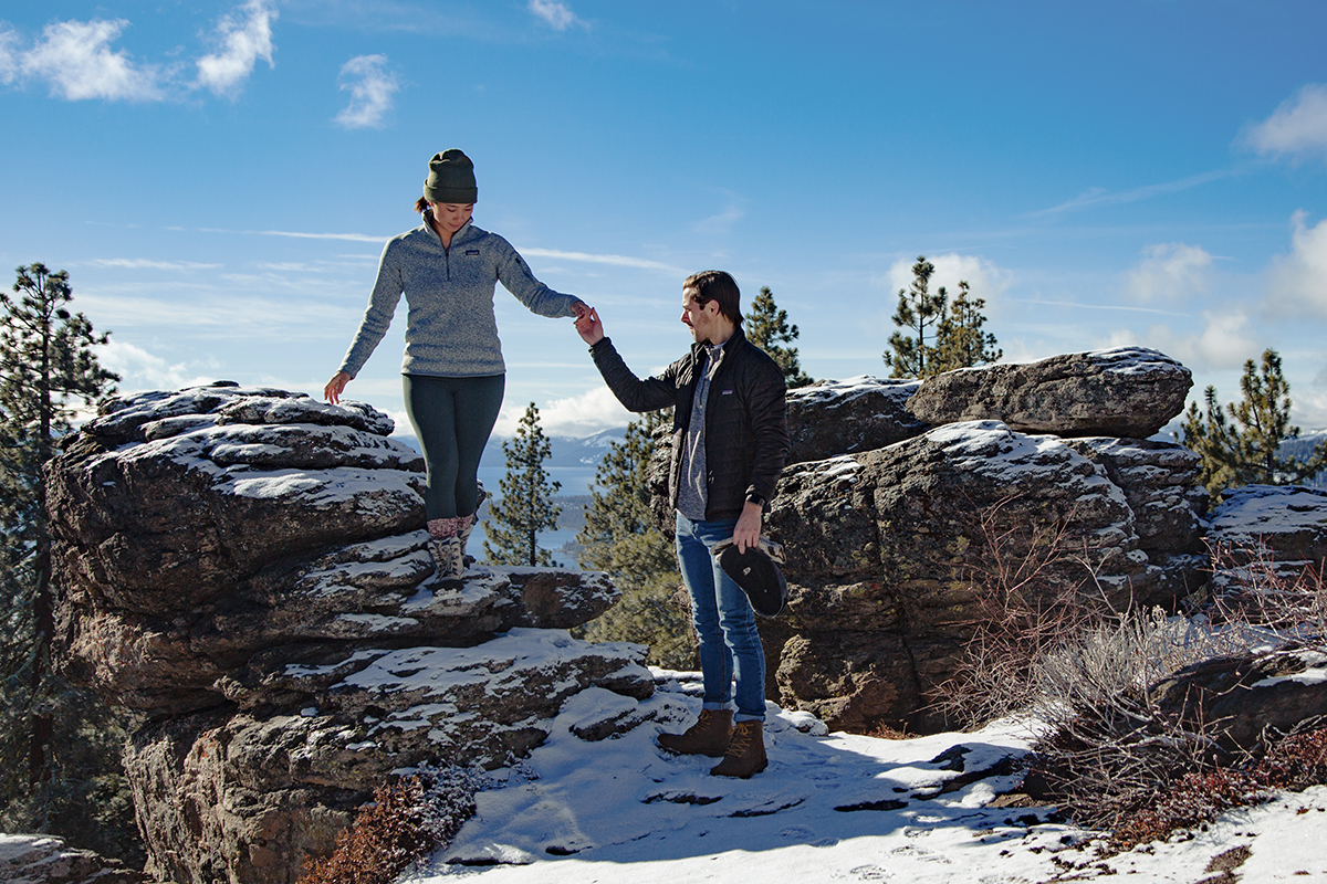 Exploring rocks together on a snowy proposal photography shoot in Lake Tahoe.