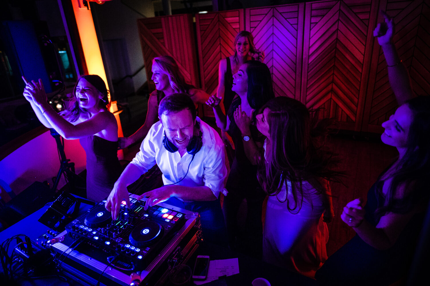 A Lake Tahoe DJ dances with bridesmaids during a colorful wedding reception.