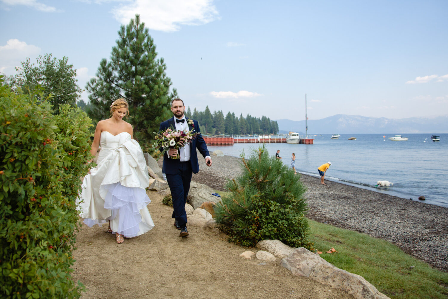 A bride and groom walk to their beach cove wedding reception at Gar Woods.