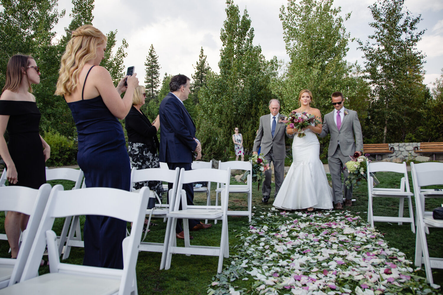 A wedding ceremony on the lawn at Gar Woods has views of Lake Tahoe with lush green trees as a backdrop.