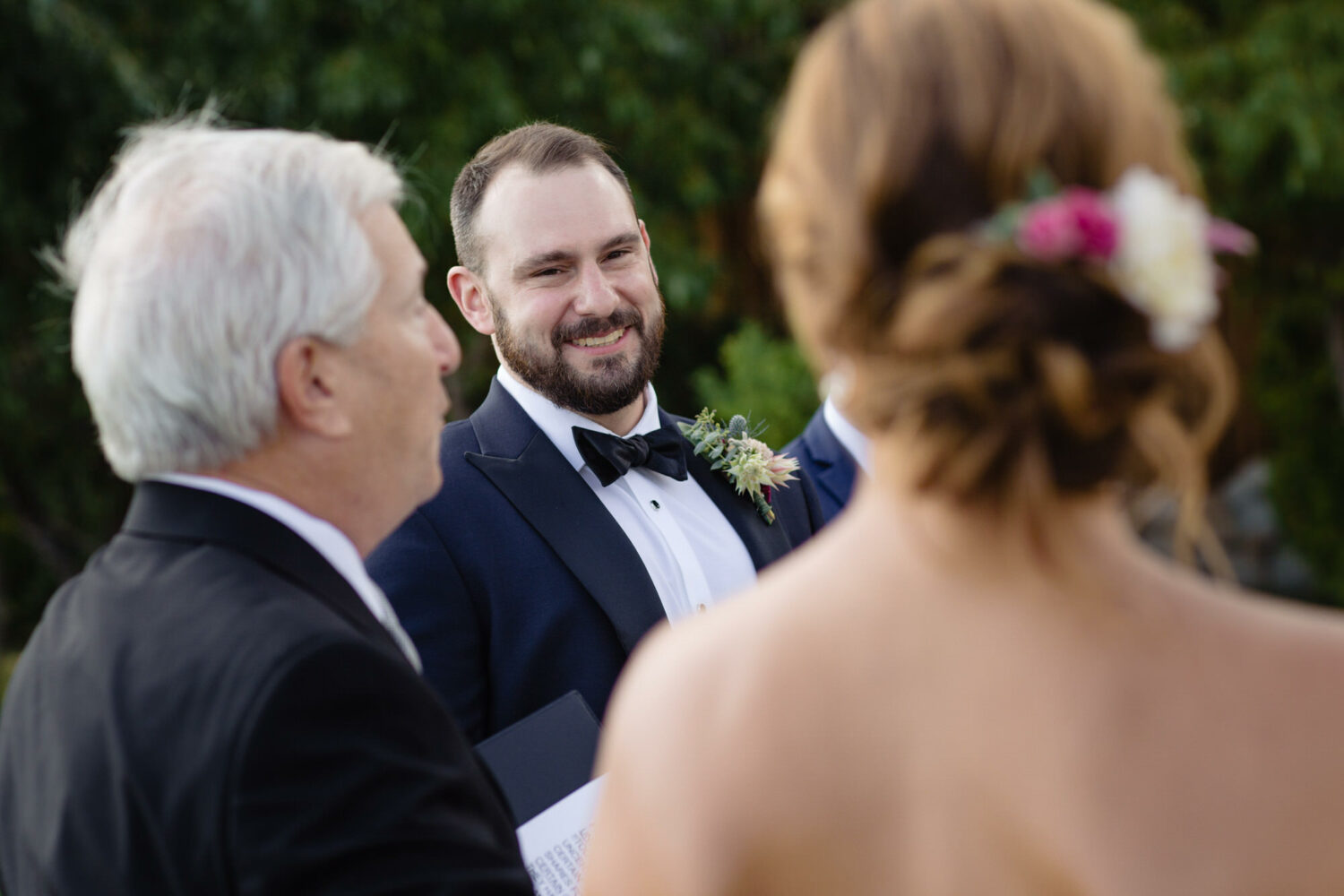 A groom wears a black bow tie to dress up an outdoor wedding at Gar Woods.