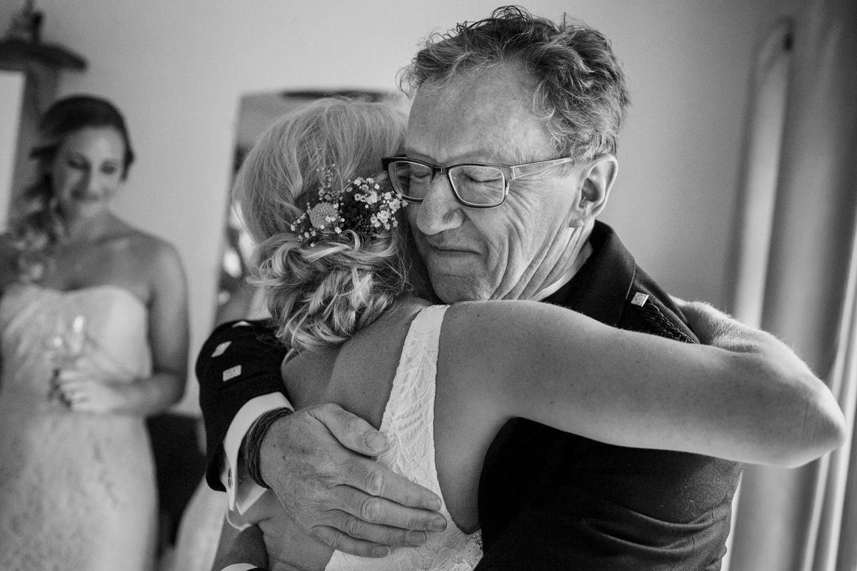A candid, emotional wedding moment as the father of the bride hugs his daughter.