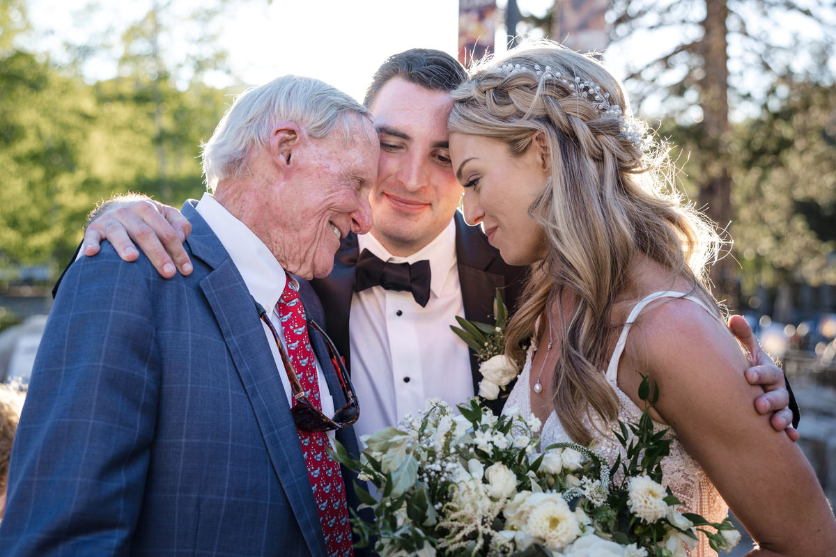 The groom hugs the bride and her grandfather.