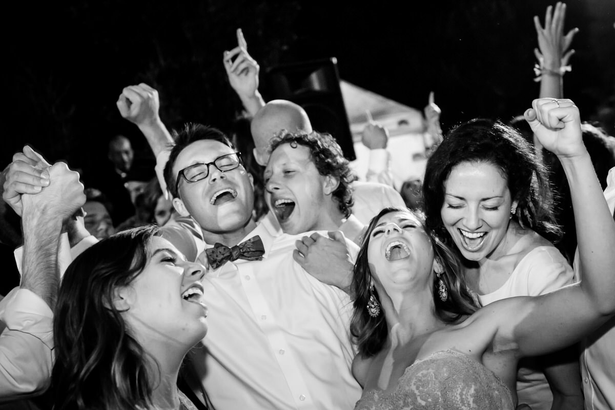 A fun candid moment of the bride and groom celebrating with friends on the dance floor.