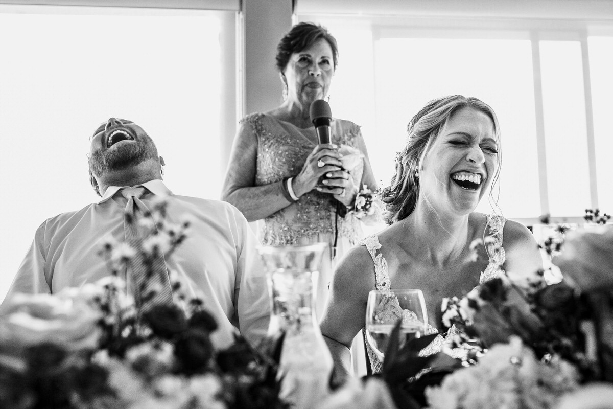 The bride and groom laugh at a funny champagne toast from the mother of the bride.