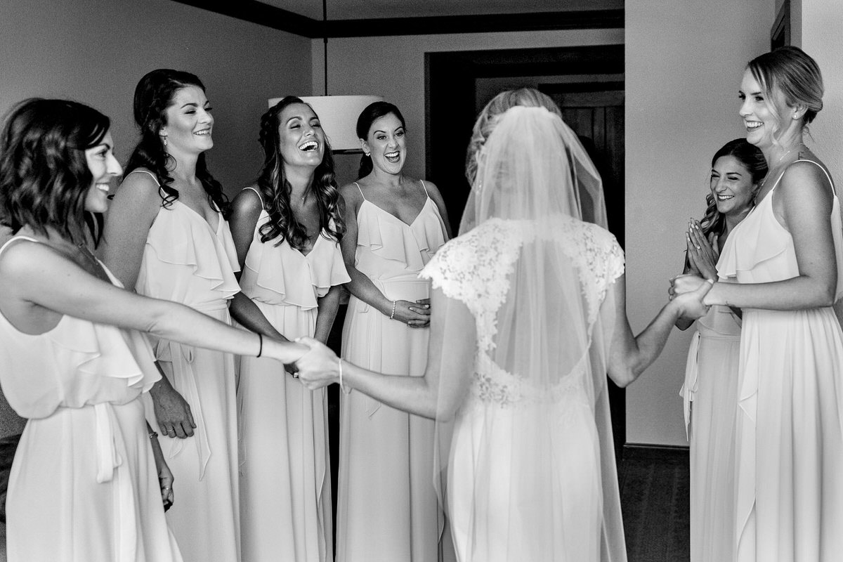 Bridesmaids react to the bride wearing her wedding dress.