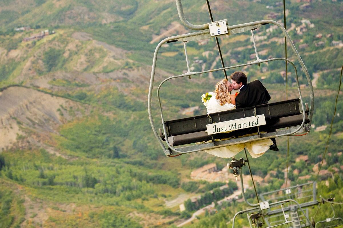 Bride and groom chairlift ride with a just married sign.