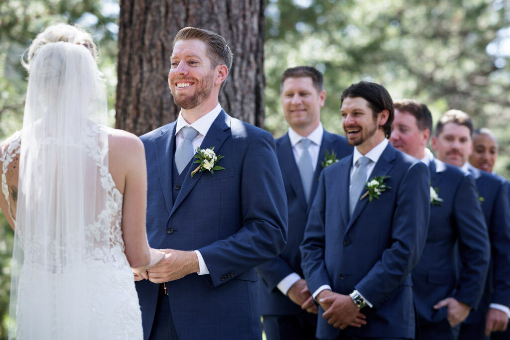 A joyful groom holds hands with his bride during their wedding ceremony.