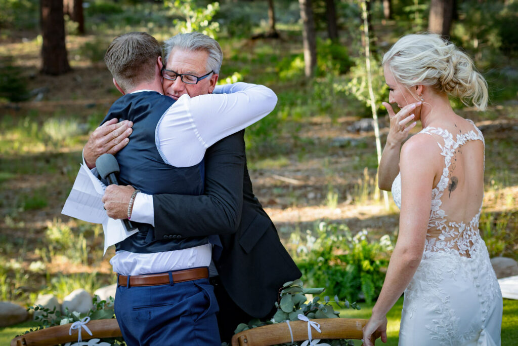 The father of the bride hugs the groom after toasting the happy couple at their Dancing Pines wedding.