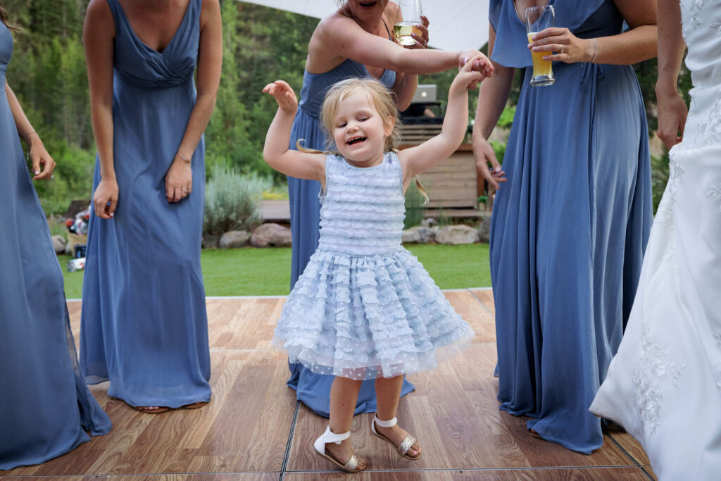 A young girl dances with bridesmaids at an outdoor summer wedding at Dancing Pines in Lake Tahoe.