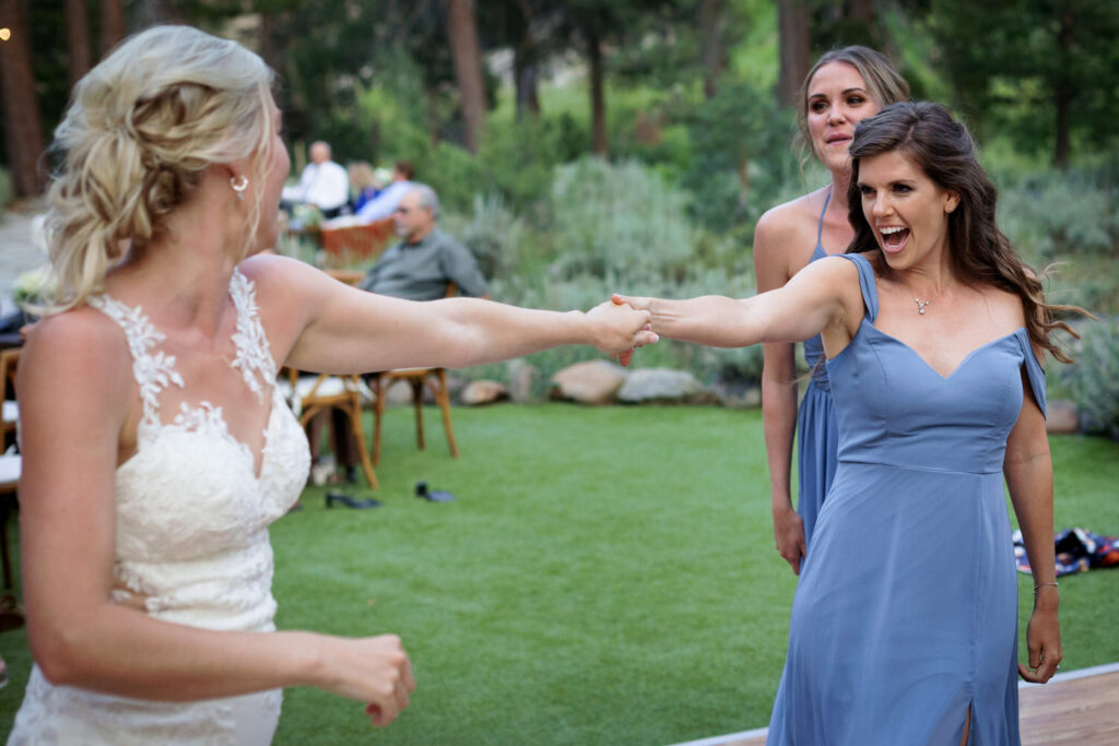 Bridesmaids and the bride dance together at an outdoor Dancing Pines wedding.