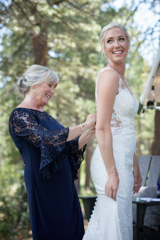 The mother of the bride helps button up the back of the wedding dress.