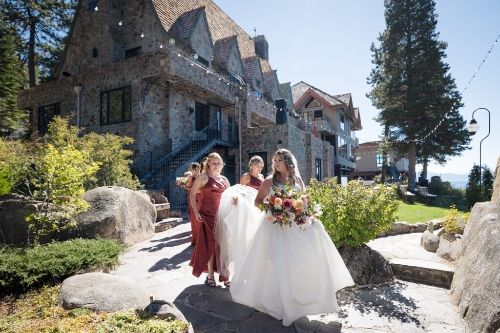 A bride and her bridesmaids walk together in front of the historic Thunderbird Lodge mansion, next to Lake Tahoe.
