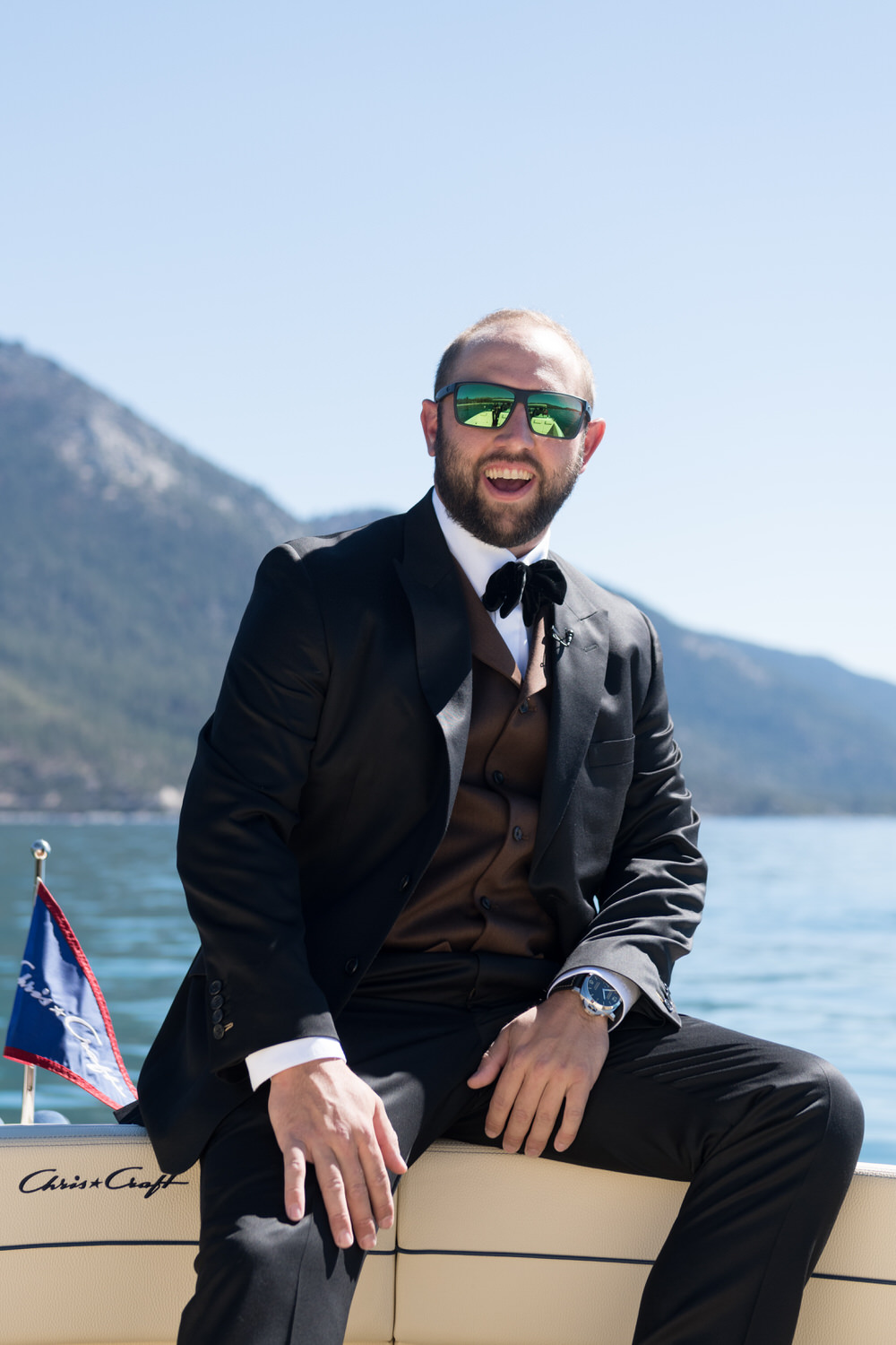 Candid photo of a groom sitting on the front of a motorboat on Lake Tahoe.