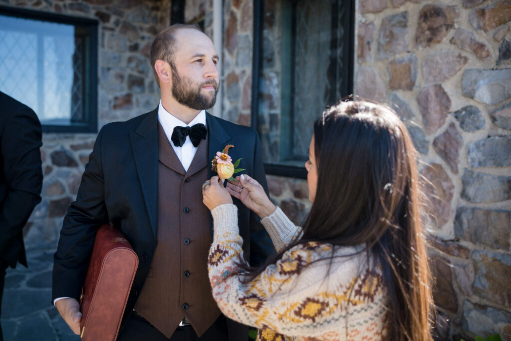 A Lake Tahoe florist pins a boutonnière on the groom's jacket lapel before a wedding at Thunderbird Lodge.