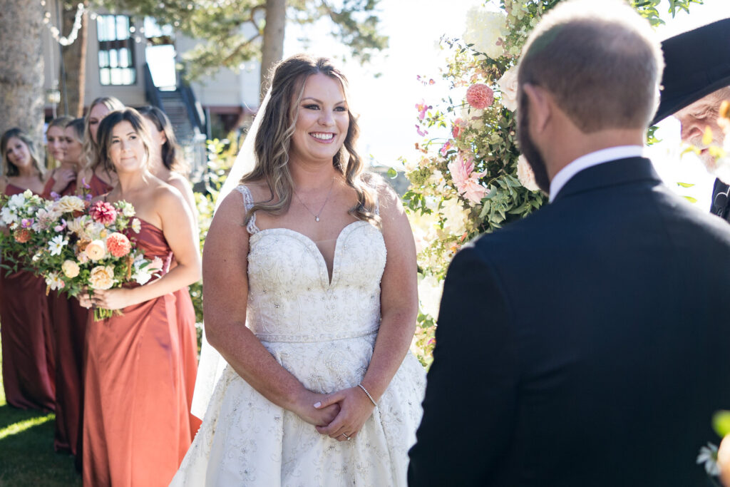 At the altar of a Thunderbird Lodge wedding, a bride smiles lovingly at her groom.