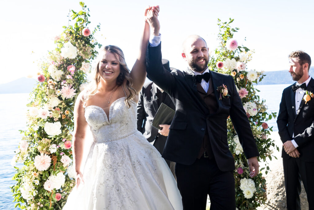 The groom and bride raise their hands in celebration after saying "I Do" at their Thunderbird Lodge wedding in Lake Tahoe.