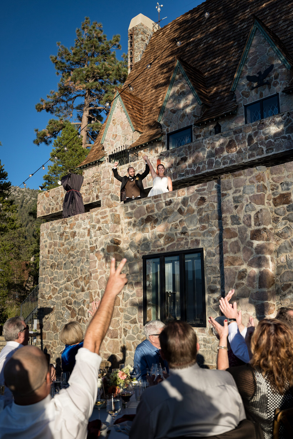 The bride and groom make their grand entrance to their Thunderbird Lodge wedding reception from the balcony and guests cheer from the lawn below.