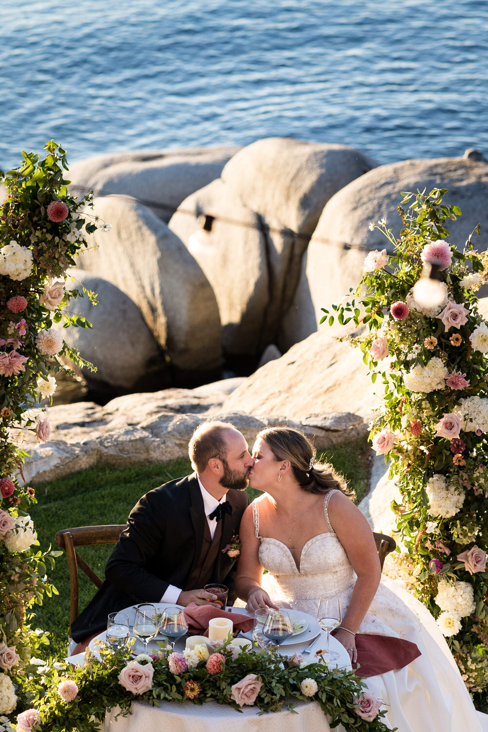 A groom kisses his bride at the sweetheart table at a Thunderbird Lodge wedding reception on the shores of Lake Tahoe.