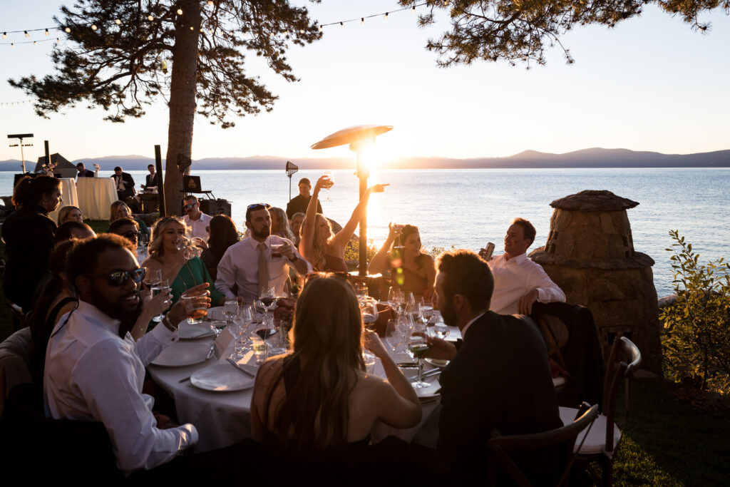 Wedding guests enjoy a sunset on the shore of Lake Tahoe at a Thunderbird Lodge wedding.