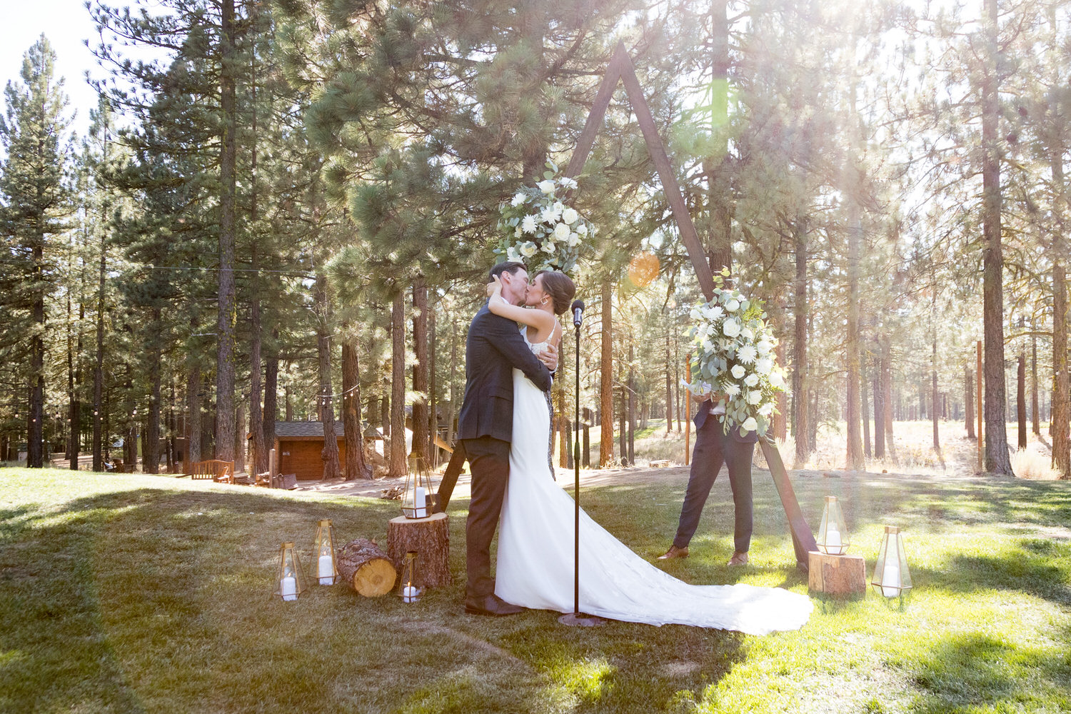 A rustic ceremony setup with logs and a wooden triangle arch.