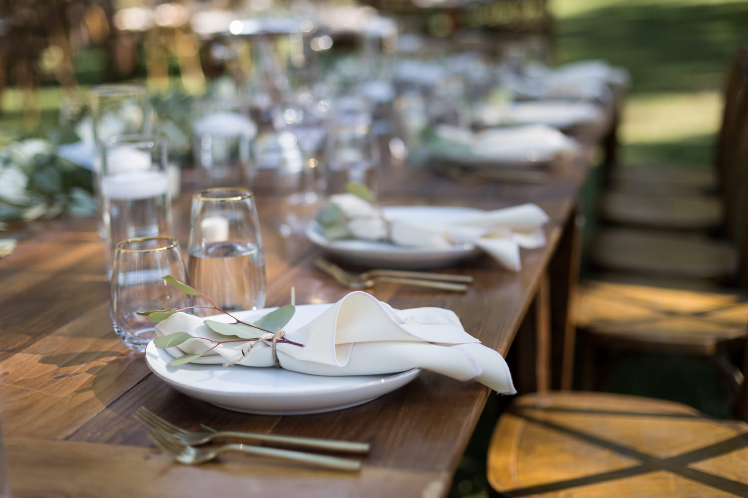A closeup view of table settings from a Chalet View Lodge wedding with Eucalyptus leaves tied onto napkins with brown twine.