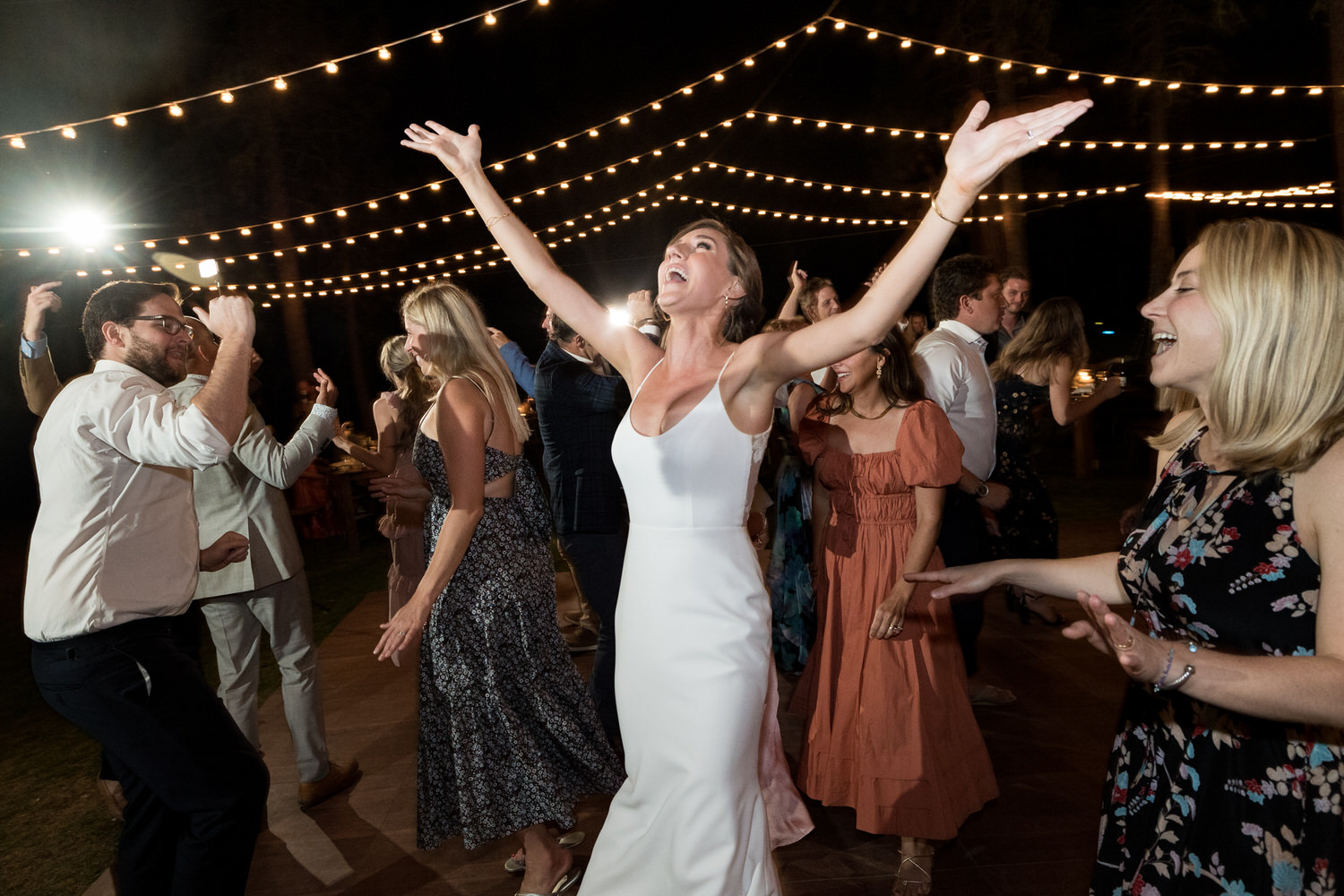 A bride throws her arms up in the air to celebrate her wedding reception at Chalet View Lodge near Blairsden-Graeagle.