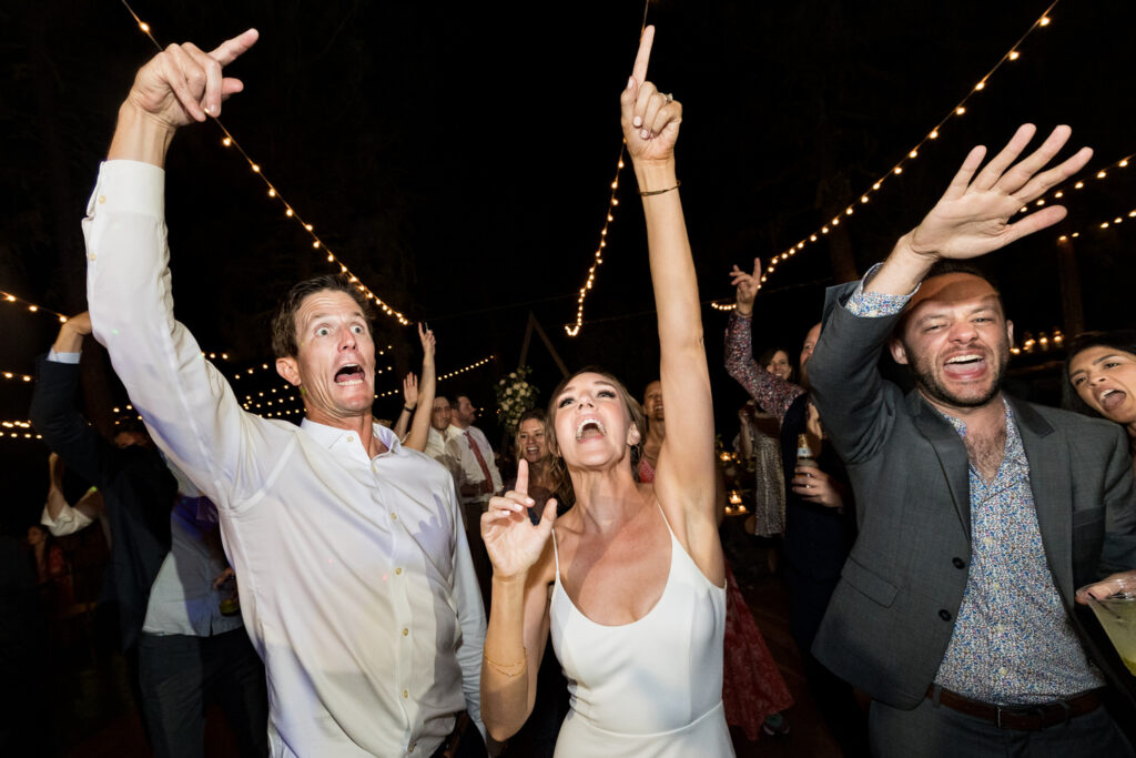 As they sing and dance together, a bride celebrates on the dance floor with her friends. 