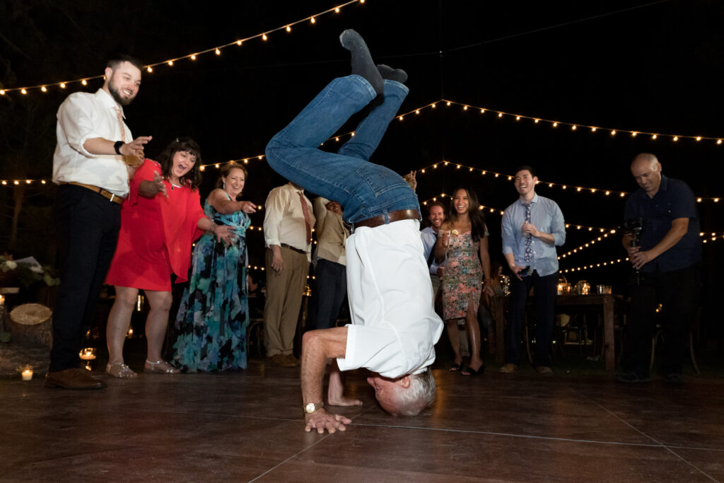 The uncle of the bride does a headstand in the center of the dance floor  during a Chalet View Lodge wedding reception near Truckee, CA.