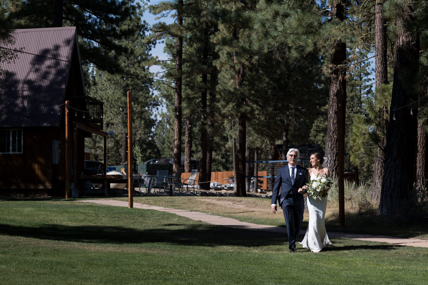 The father of the bride walks his daughter to the ceremony venue at Chalet View Lodge.
