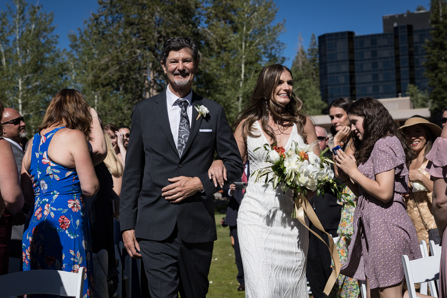 The father of the bride walks his daughter down the aisle at an outdoor summertime wedding at Everline Resort and Spa.