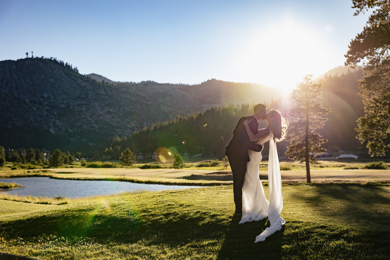 Summertime wedding at Everline Resort & Spa. Bride and groom kissing on the edge of the golf course as the sun sets behind the mountains.