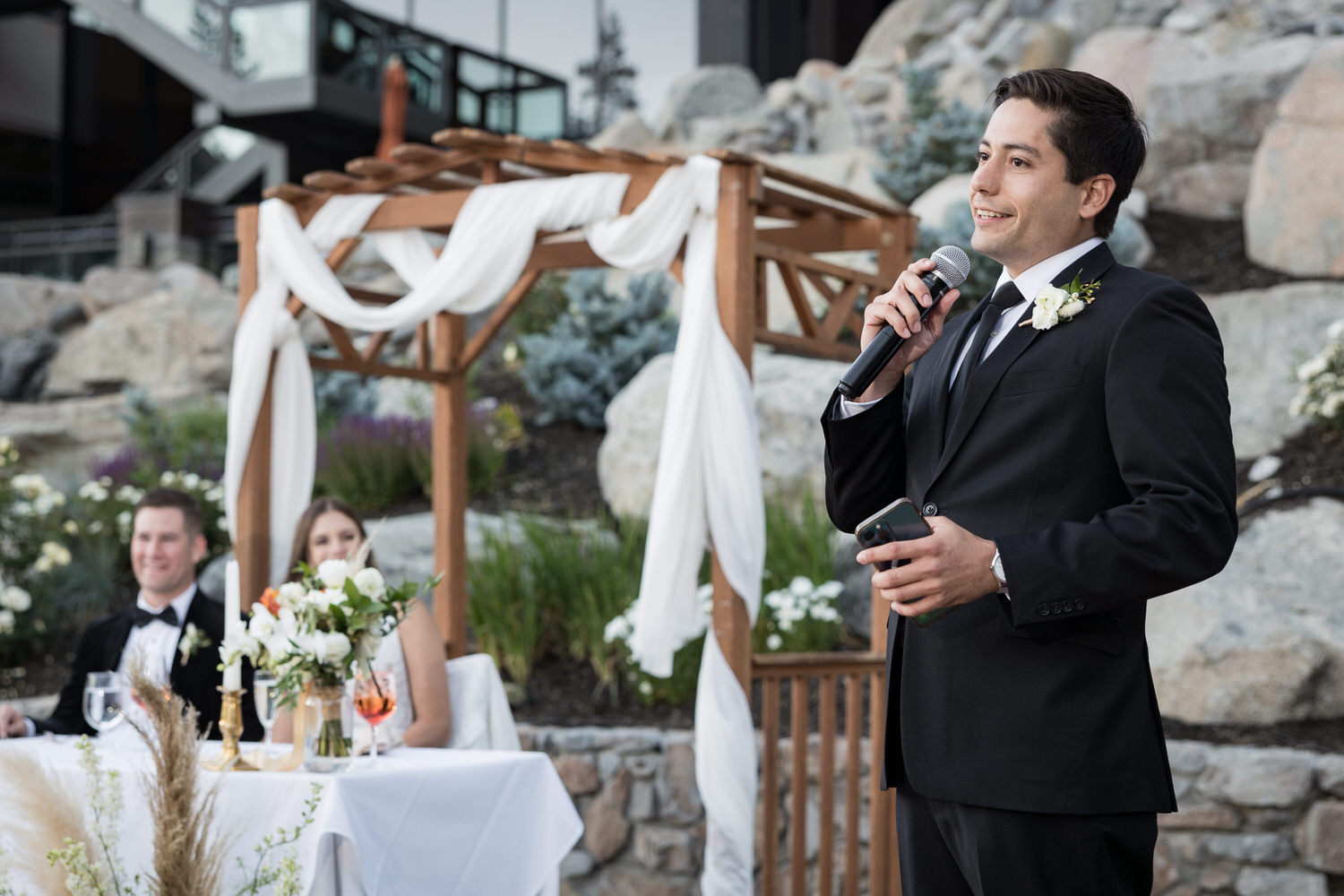 Best man making a funny wedding speech at an outdoor reception.