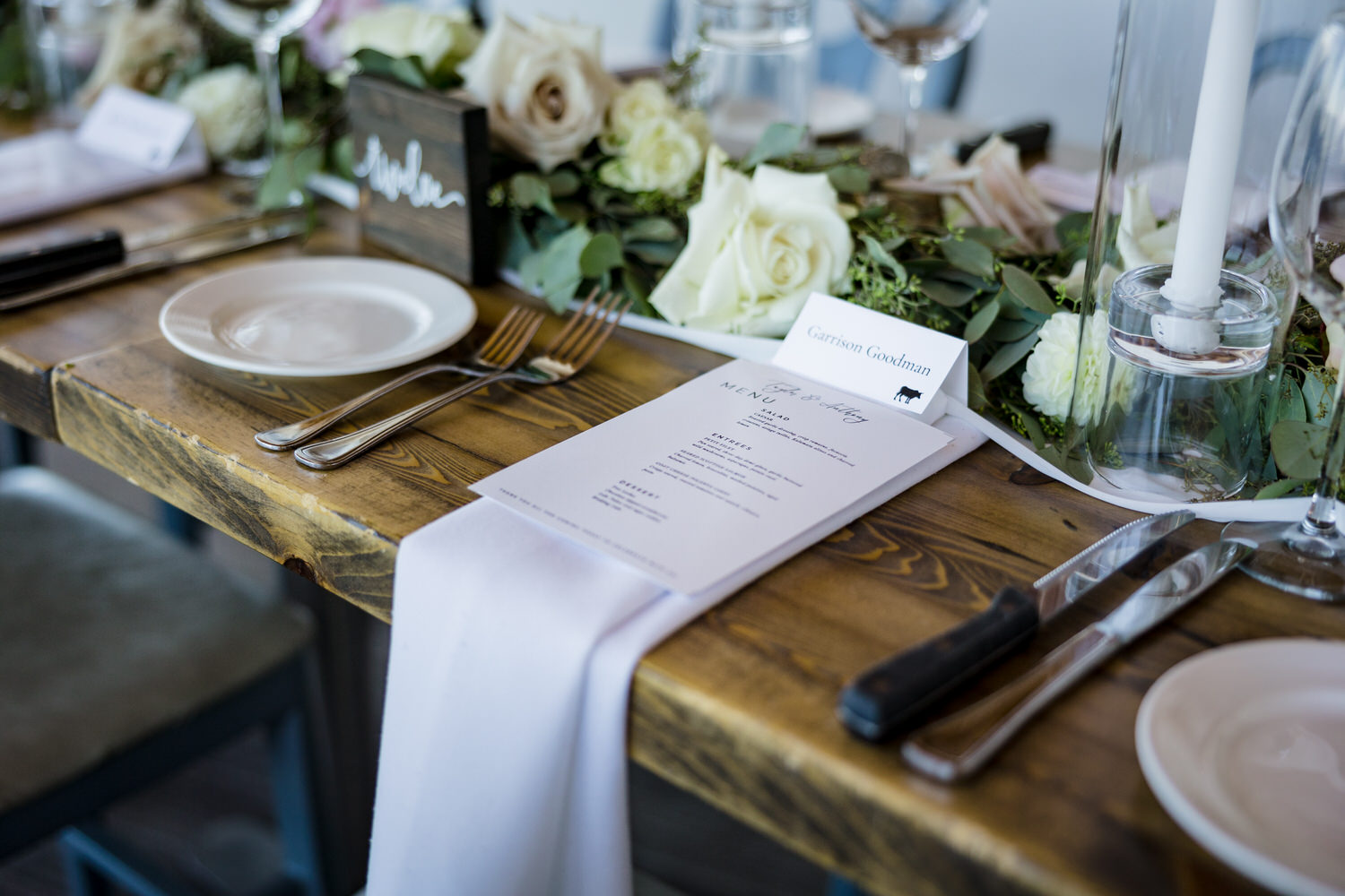 Dining table setting for a High Camp wedding with white flowers and eucalyptus leaves.