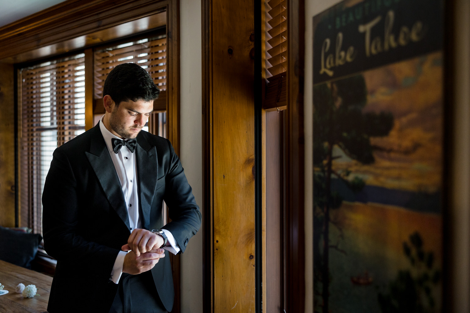 A groom gets ready in a hotel room at the Village at Palisades Tahoe.