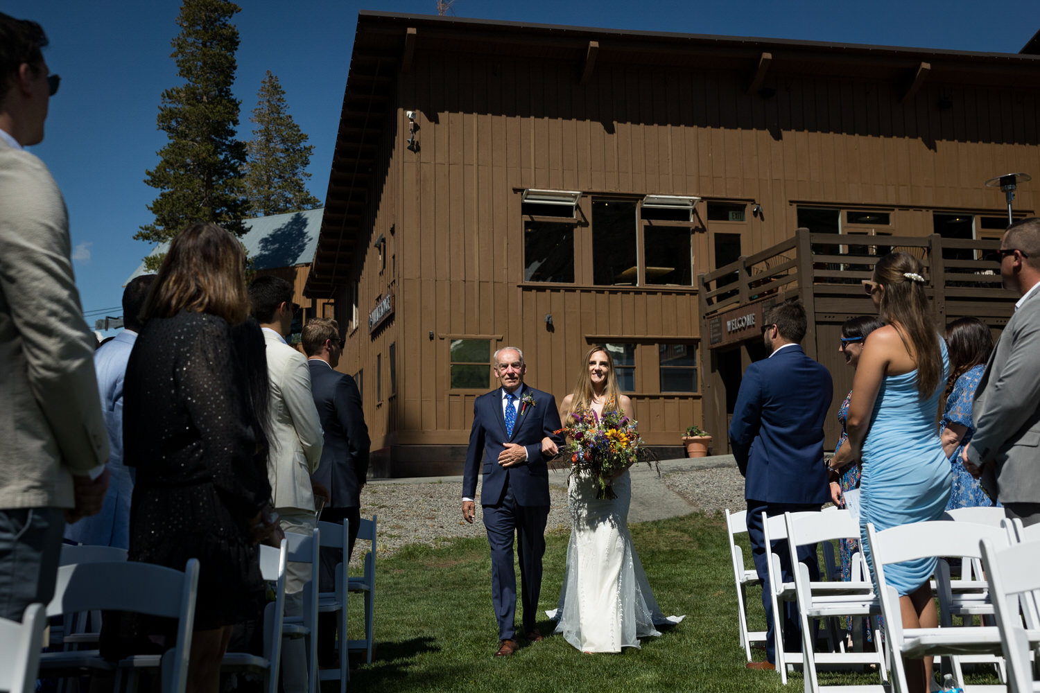 A bride walks down the aisle with her father in front of the iconic Sugar Bowl Lodge.