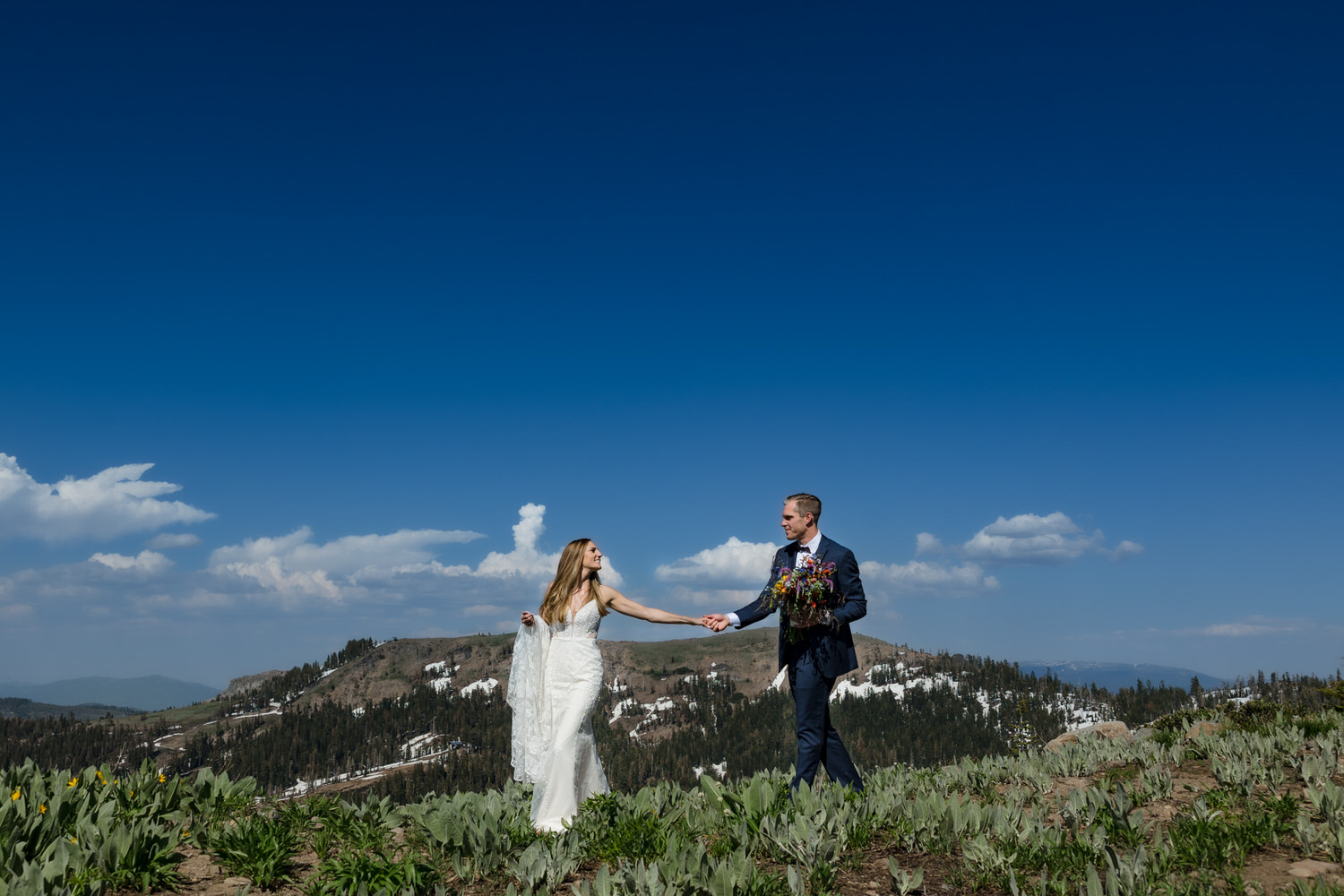 A bride and groom walk hand-in-hand atop Mount Disney at their summer Sugar Bowl Resort wedding.