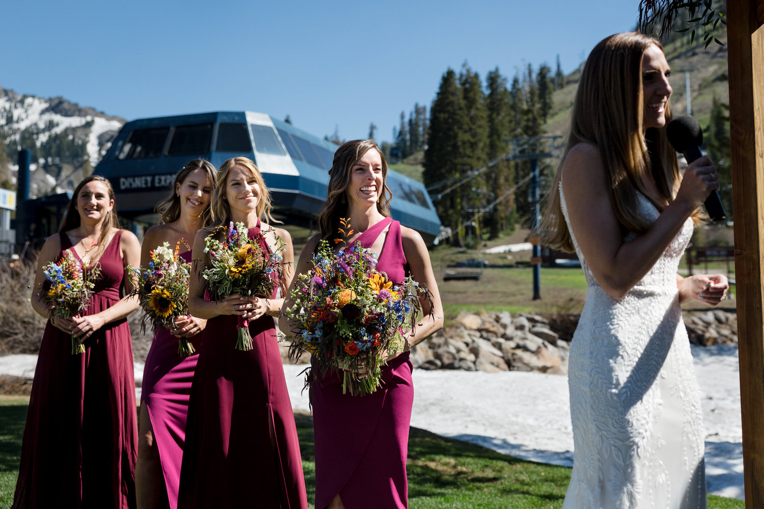 Maroon bridesmaid dresses and colorful floral bouquets during a wedding ceremony next to Disney Express chairlift.