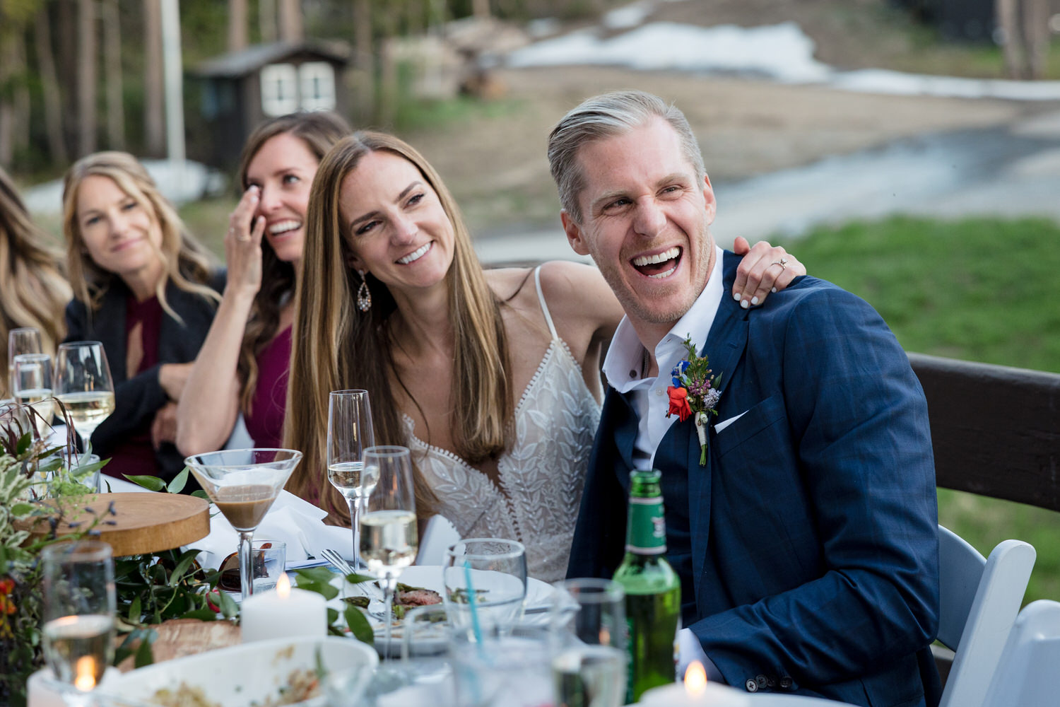 The bride and groom react to a funny champagne toast at their outdoor ski resort wedding.