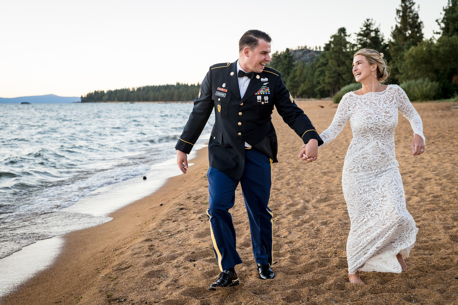 A joyous, candid portrait of a bride and groom walking on the beach in South Lake Tahoe.