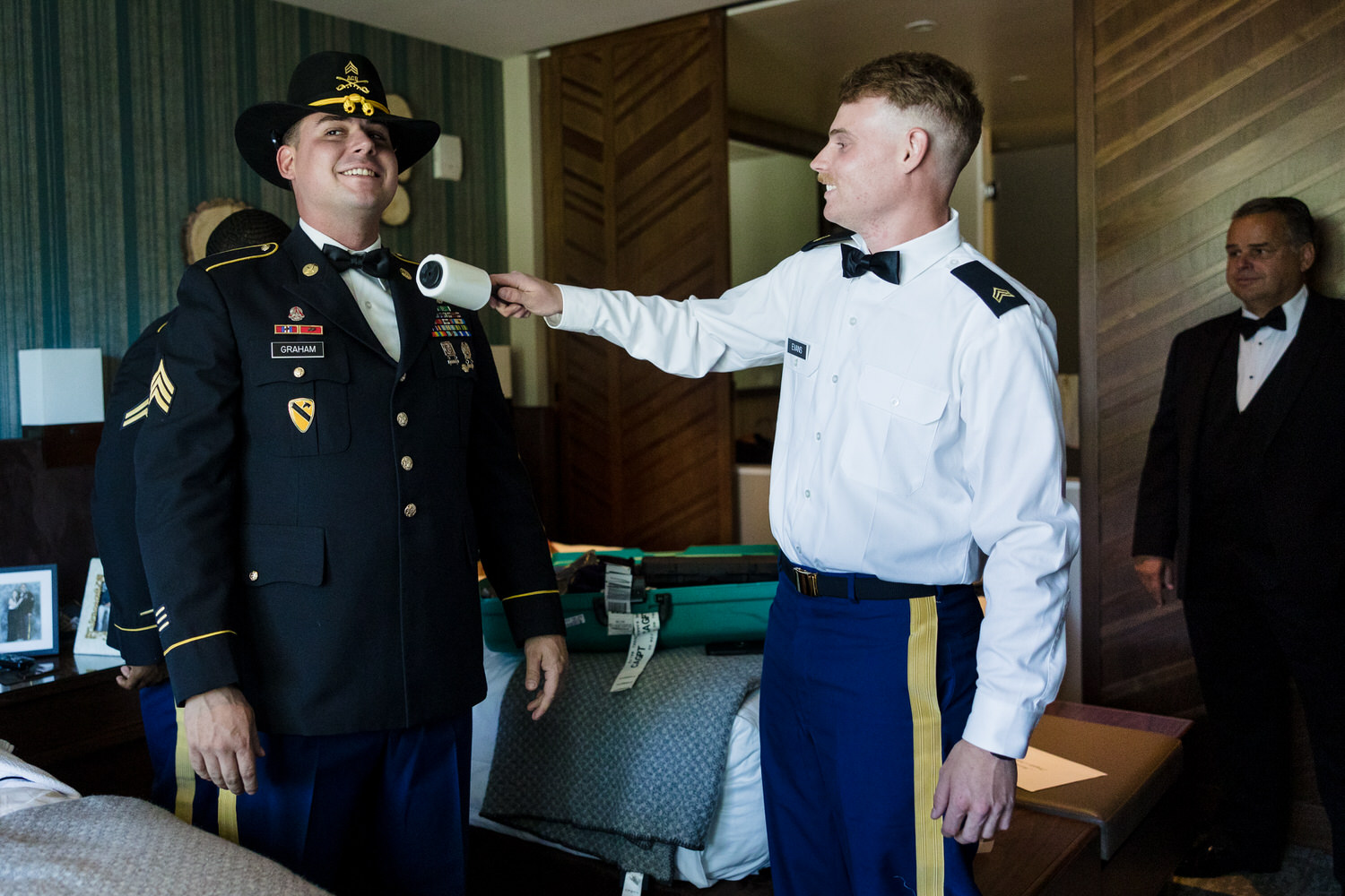 A groomsman removes lint from a groom's Air Force dress blues.