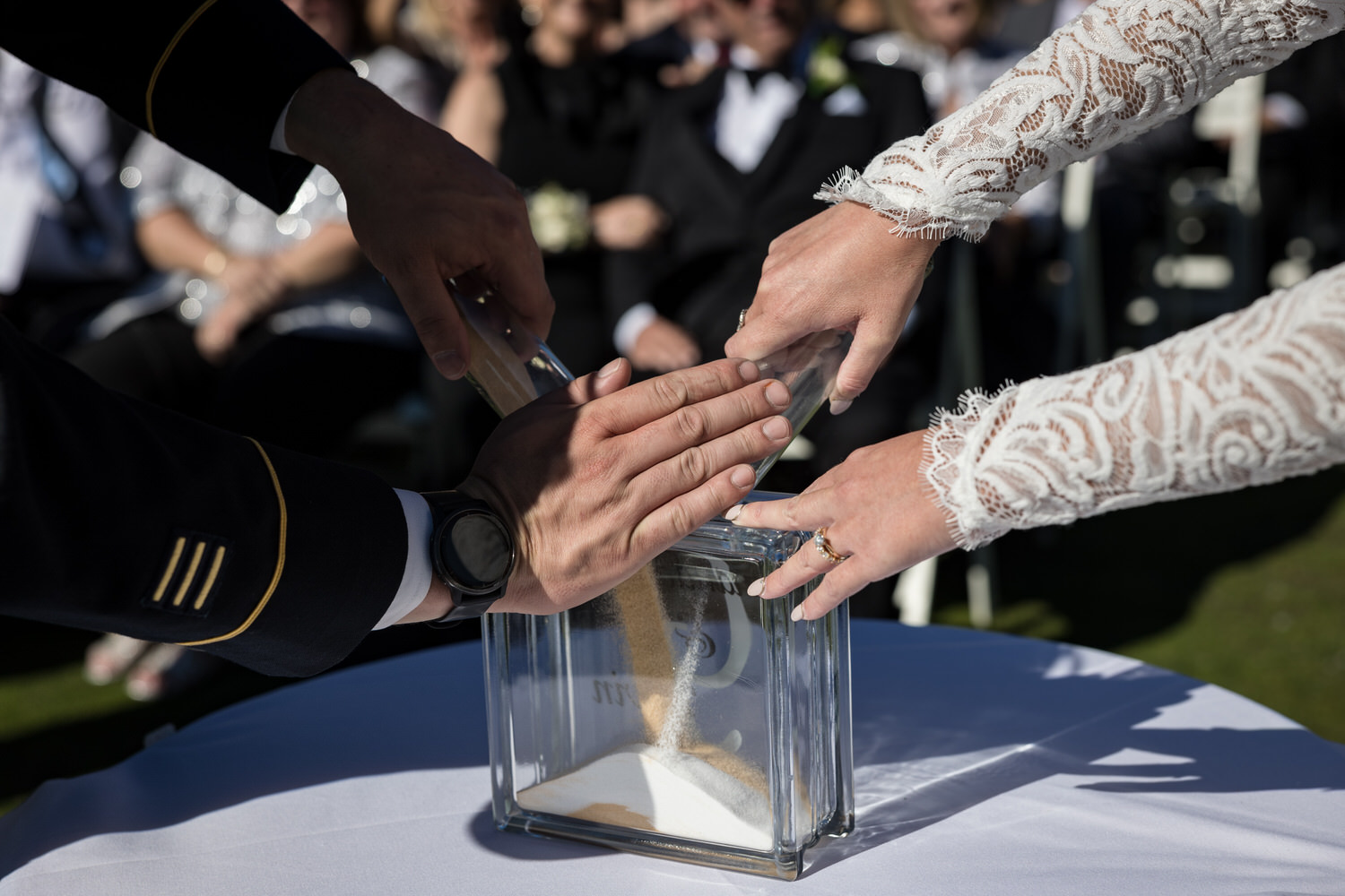 Zoomed in view of a bride and groom's hands during a unity sand ceremony.