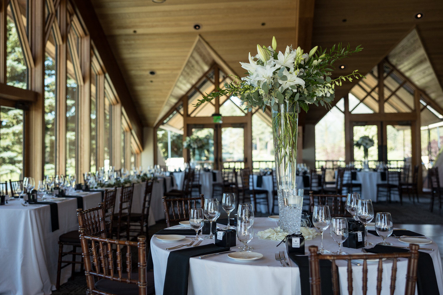 Tall glass reception table centerpieces with white flowers and black napkins at a North Room wedding reception.