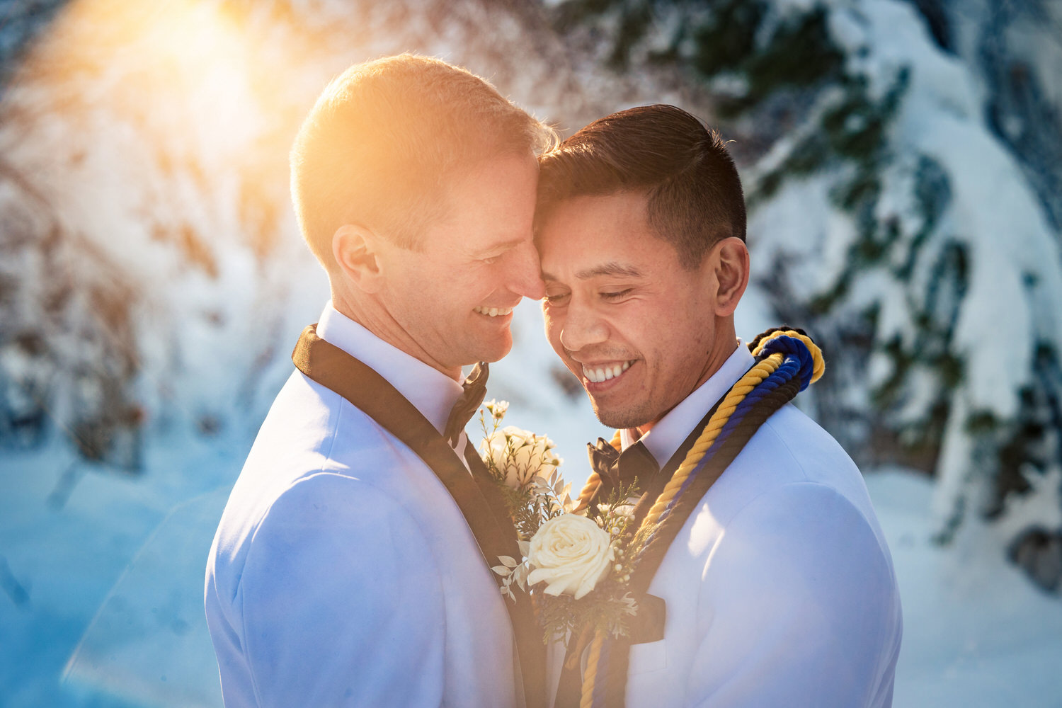 Sunset portrait in winter of two grooms wearing white tuxedos.